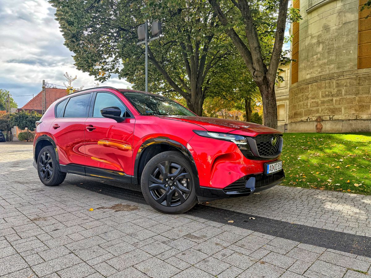 Piros Mazda CX-5 Homura Plus SUV elölnézetből, fekete keréktárcsákkal, őszi környezetben.
