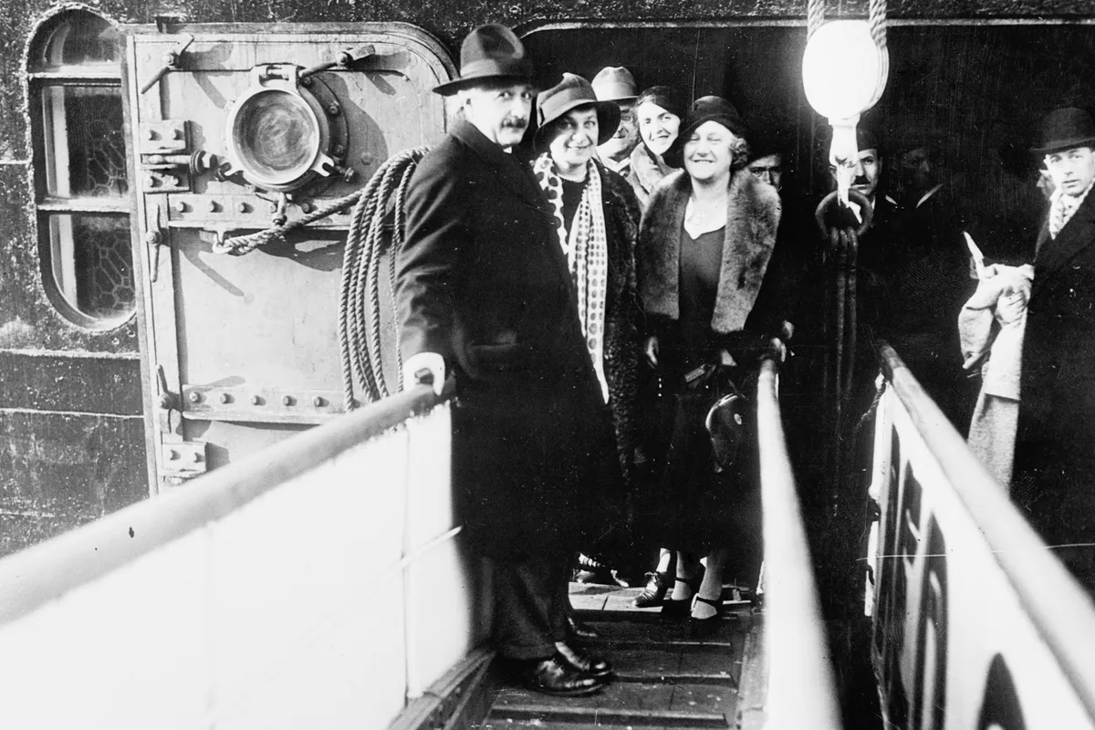Pictured above as they boarded the S.S. Belgenland to sail for the United States where Dr. Einstein is to make scientific observations in California, when they paused, while walking down the gangplank to pose for the photographer.