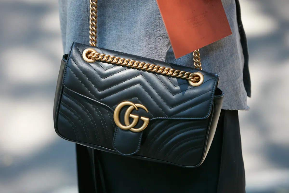MILAN - JUNE 19: Woman with black Gucci leather bag and chain before Giorgio Armani fashion show, Milan Fashion Week street style on June 19, 2017 in Milan.