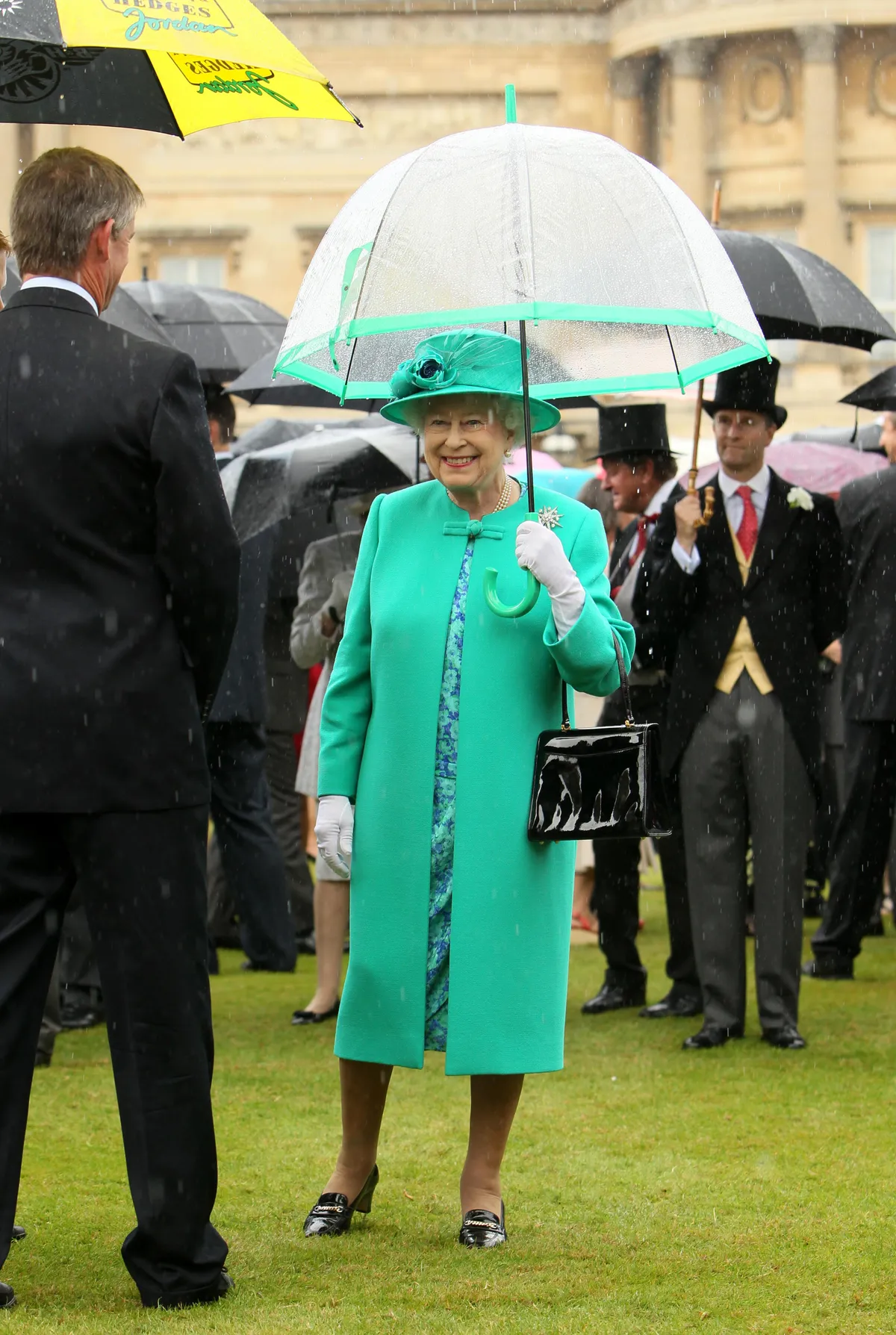 Britain's Queen Elizabeth II shelters from the rain under an umbrella as she hosts a garden party at Buckingham Palace, in central London.