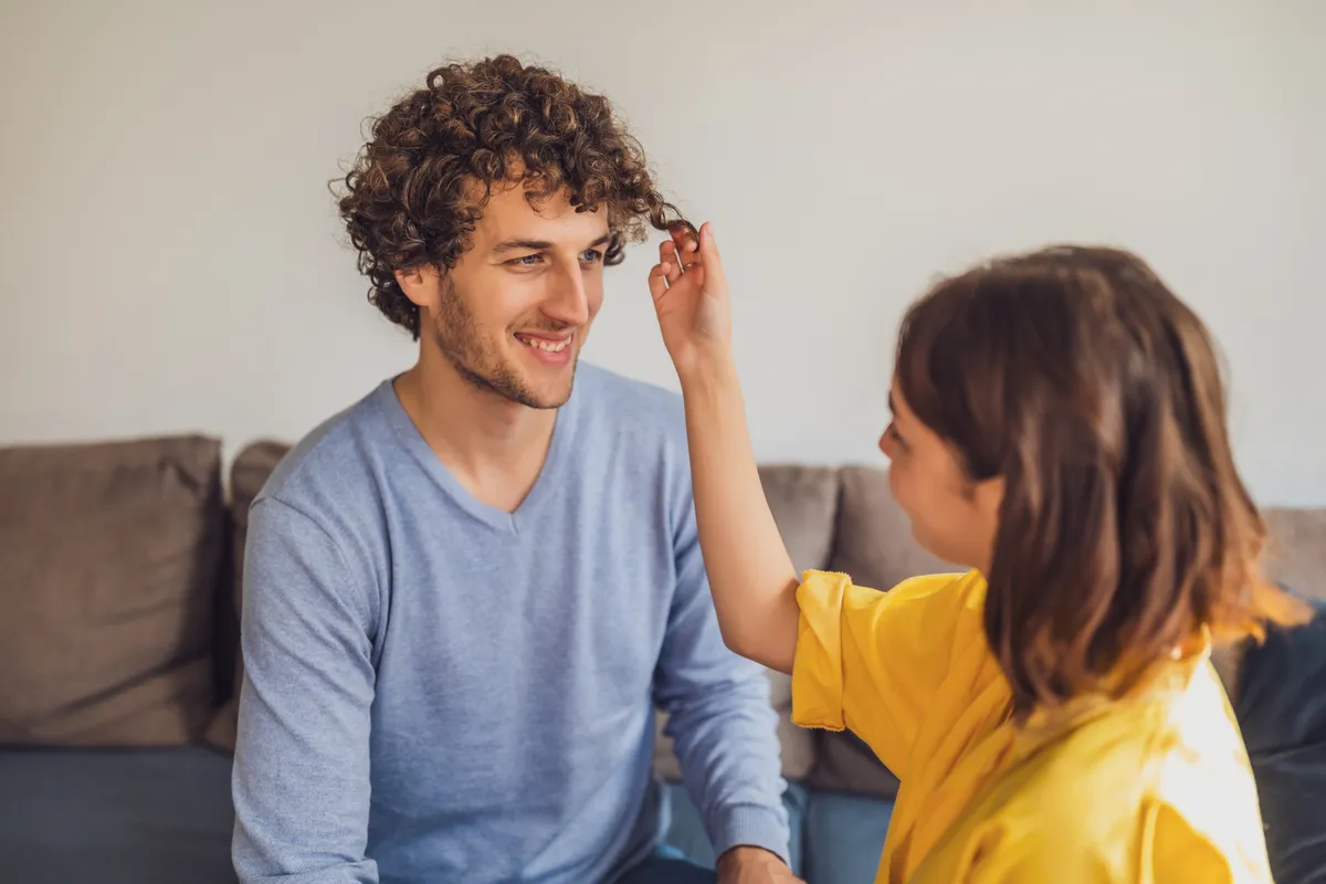 Portrait of young happy couple in love. Woman is playing with man's curly hair.
