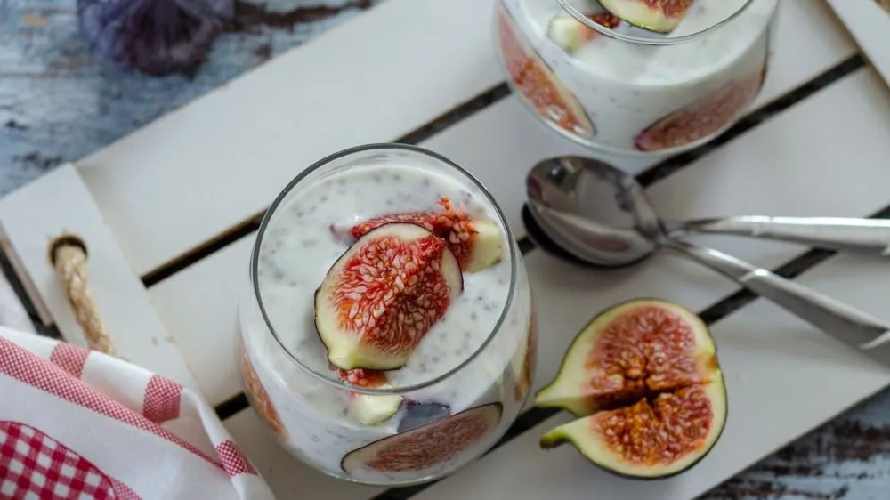Healthy breakfast from natural ingredients .Homemade yogurt, slice of the fig, chia seeds and yogurt in glasses on the wooden background, top view.