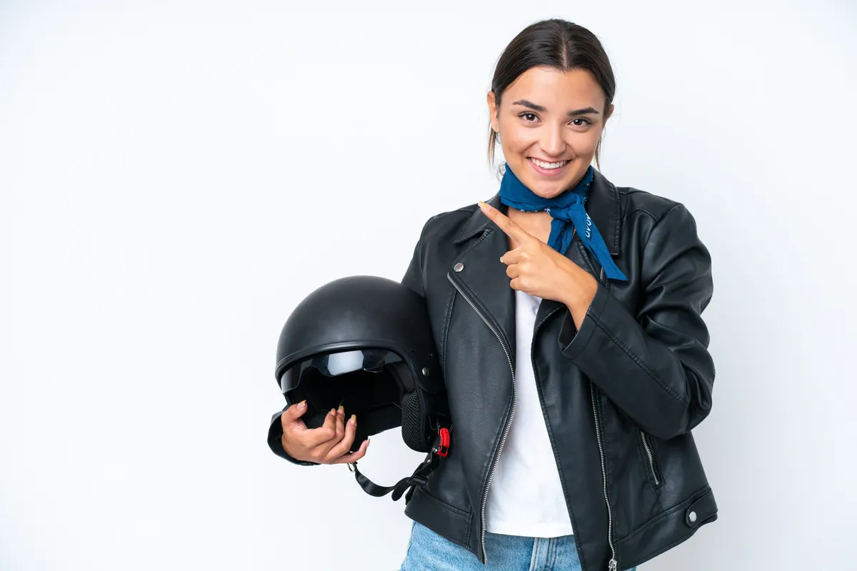 Young caucasian woman with a motorcycle helmet isolated on blue background pointing to the side to present a product
