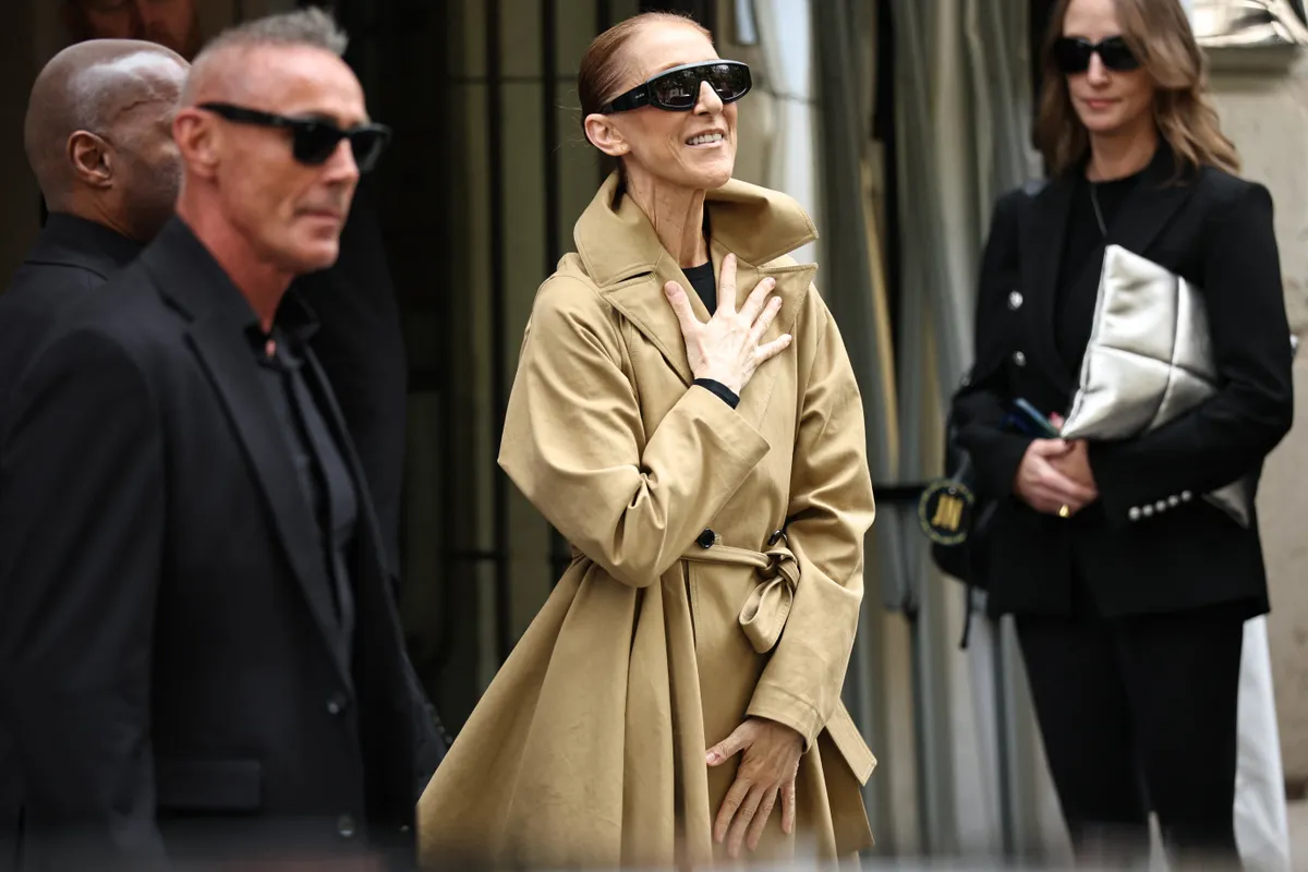 Canadian singer Celine Dion (C) acknowledges fans as she arrives at Hotel Le Royal Monceau in Paris on August 28, 2026, ahead of her series of concerts in the French capital. Celine Dion, 58, announced in late March, in a video and a message projected onto the Eiffel Tower, her return to the stage, in Paris, after six years away from the public, between the pandemic and persistent health problems. She has suffered since 2022 from stiff person syndrome, a rare and incurable neurological condition. (Photo by SIMON WOHLFAHRT / AFP)