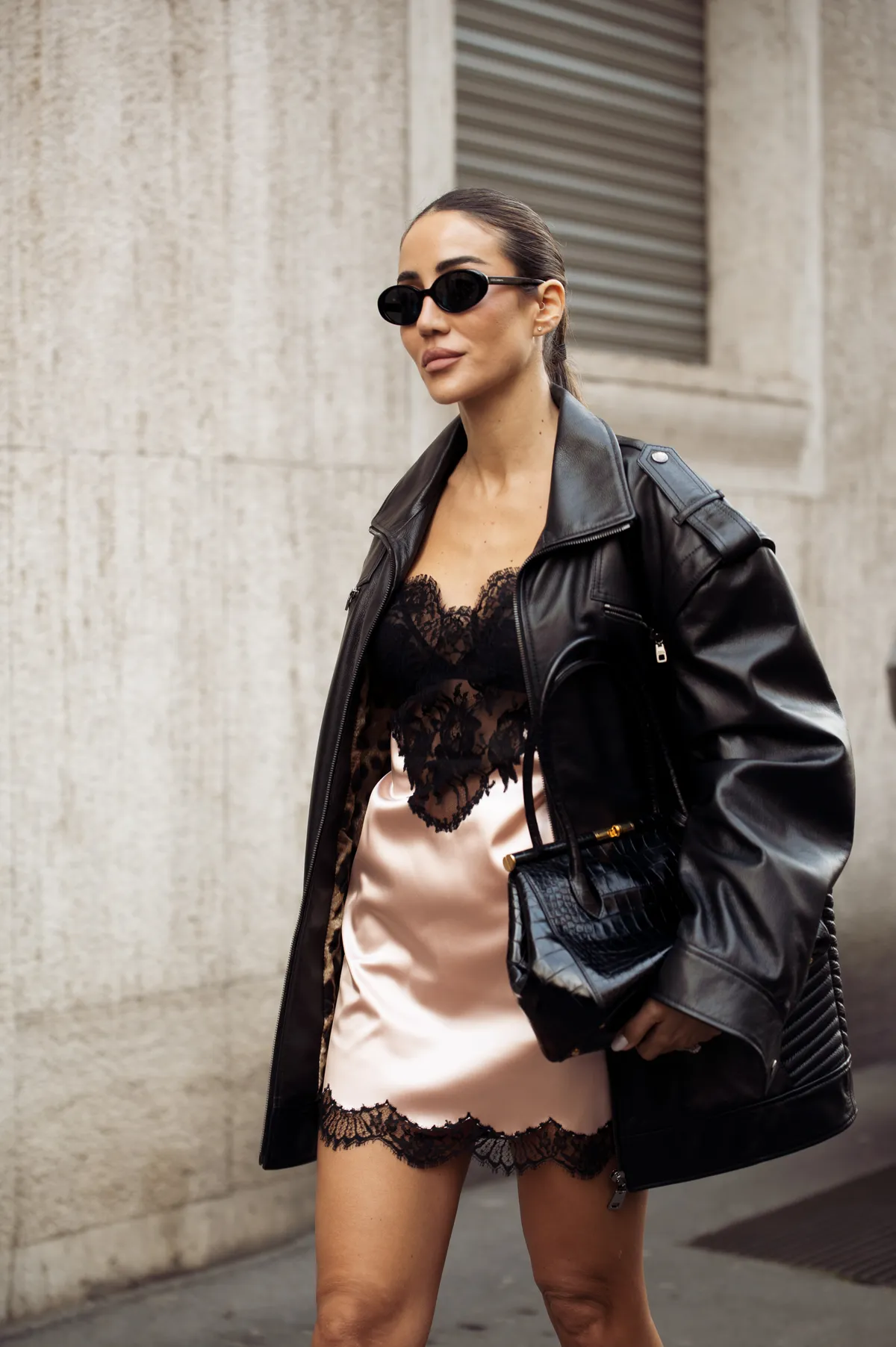 MILAN, ITALY - MARCH 01: Tamara Kalinic wears black leather jacket, black bag, peach or pale orange silk mini slip dress with black lace and sunglasses outside the Dolce & Gabbana fashion show during the Milan Fashion Week Womenswear Fall/Winter 2025/2026 on March 01, 2025 in Milan, Italy. (Photo by Raimonda Kulikauskiene/Getty Images)