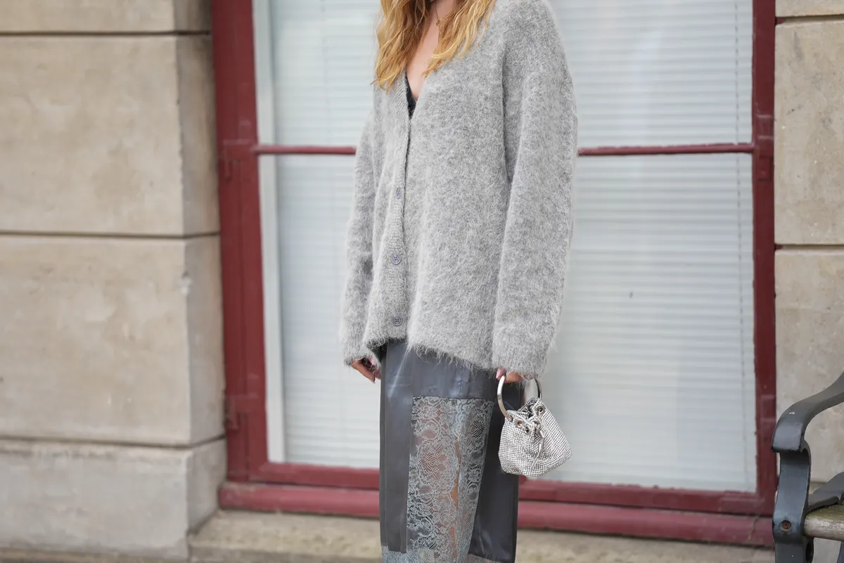 COPENHAGEN, DENMARK - AUGUST 6: Sonia Lyson, attending the Munthe Show during Copenhagen Fashion Week SS26, is seen wearing a light gray Munthe mohair buttoned cardigan with V neck, long sleeves and oversized fit; a Munthe sleek gray midi skirt with lace details at the bottom; a Jimmy Choo Micro Bon Bon silver bucket bag with rhinestones; a gold necklace; during Copenhagen Fashion Week day three on August 6, 2025 in Copenhagen, Denmark.  (Photo by Moritz Scholz/Getty Images)