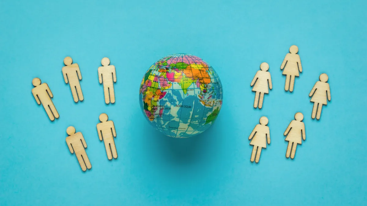 Groups of wooden men and women and a model of the globe on a blue background. Earth Day. The concept of environmental protection.