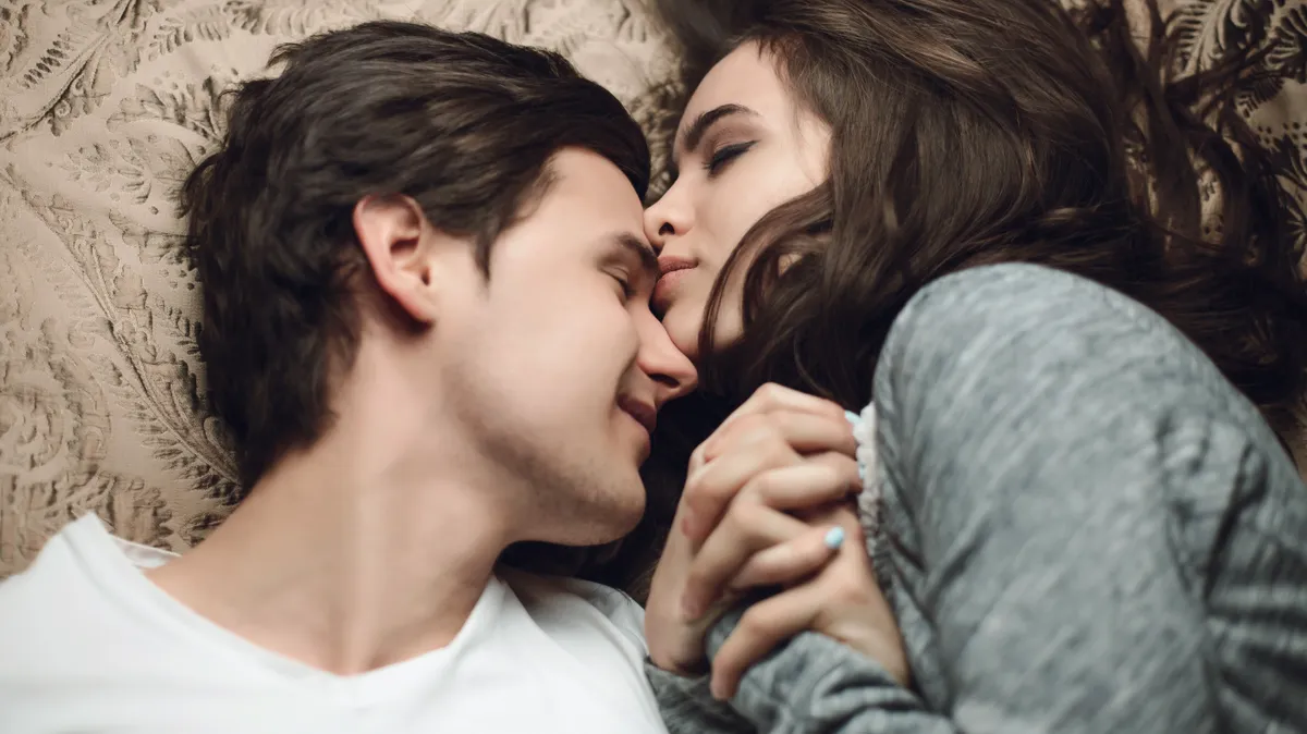 Beautiful,Brunette,Girl,And,Guy,Lying,In,Bed,And,Holding