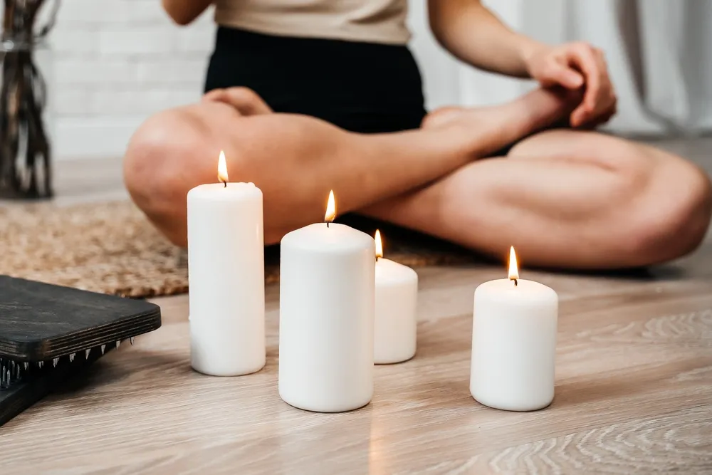 Nő meditáló pózban a gyertya lángja előtt