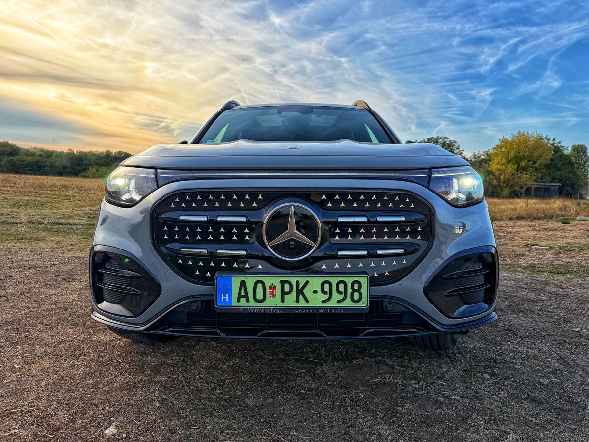 Szürke, elektromos Mercedes-Benz GLB elölnézetből, világító fényszórókkal.