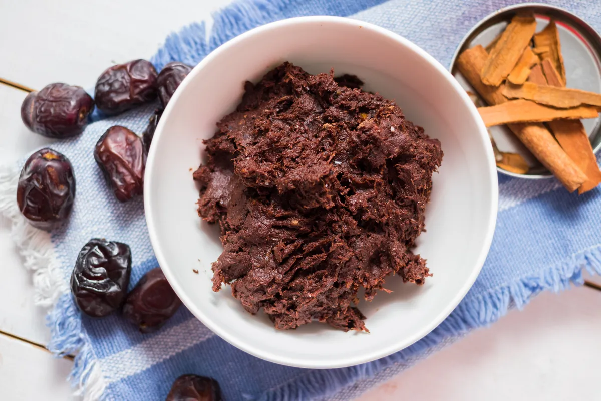 Sweet chocolate dough mix with dates, cocoa powder, banana, carob powder, coconut oil, coconut, walnuts, almonds. Raw, vegan, vegetarian healthy food concept. Ready to make brownie, cookies, truffles.