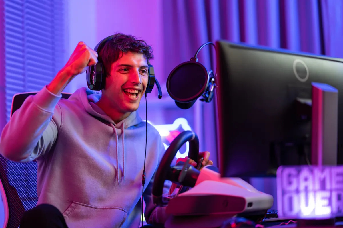 Caucasian young esport male gamer play online video game on computer. Handsome man gaming player feel happy and excited, enjoy technology broadcast live streaming while plays cyber tournament at home.
