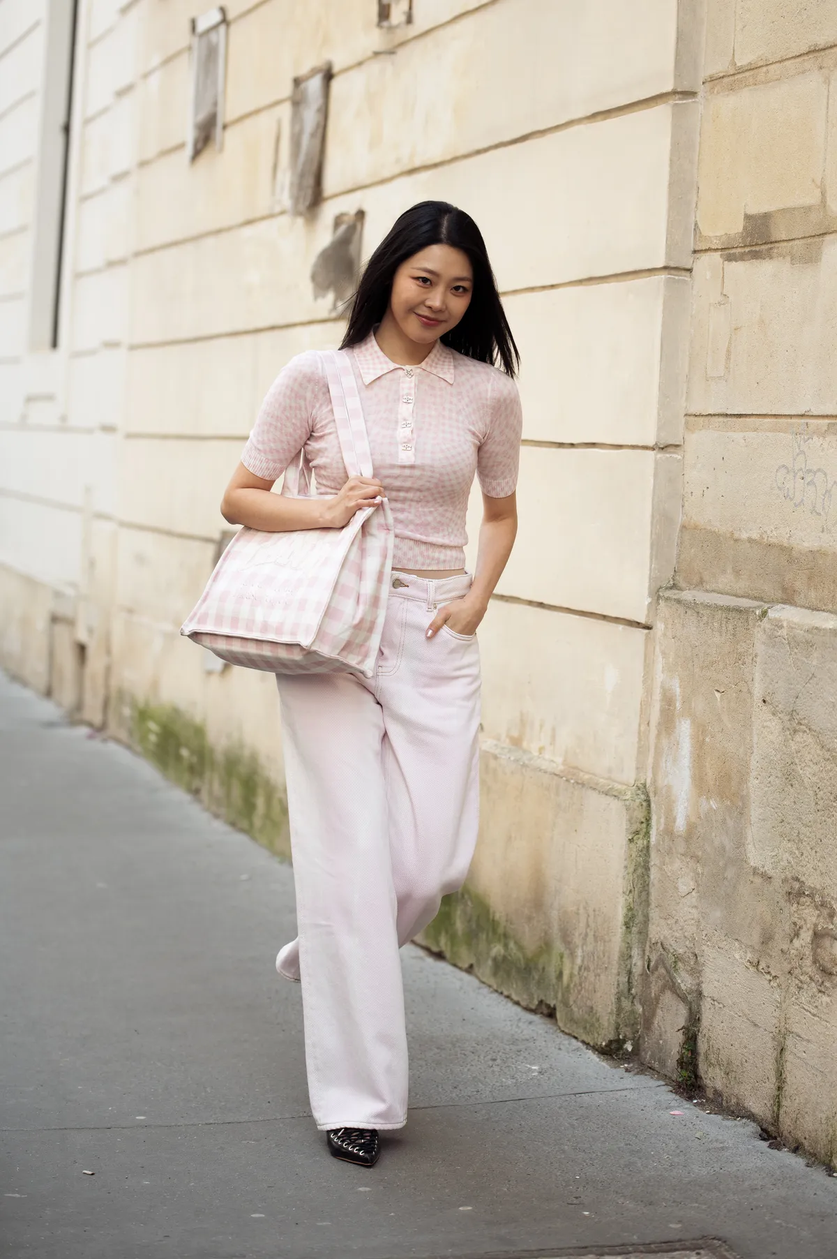 PARIS, FRANCE - MARCH 04: A guest wears light pink Ganni jeans, pink and white checkered short sleeve top, pink and white checkered bag from Ganni outside the Ganni fashion show during the Womenswear Fall/Winter 2025/2026 as part of Paris Fashion Week on March 04, 2025 in Paris, France. (Photo by Raimonda Kulikauskiene/Getty Images)