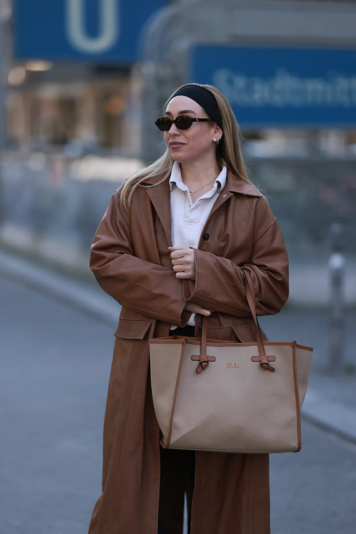 BERLIN, GERMANY - APRIL 09: Sonia Lyson seen wearing black cotton headband, Corlin Eyewear slim oval-shaped dark brown sunglasses, Worst Behavior white cotton polo sweater giving the look a sporty, laid-back vibe, Herskind long, cognac brown leather trench coat, Lululemon simple black comfortable and athleisure-inspired leggings, Gianni Chiarini large beige tote bag with brown leather trim and monogrammed initials, on April 09, 2025 in Berlin, Germany. (Photo by Jeremy Moeller/Getty Images)
