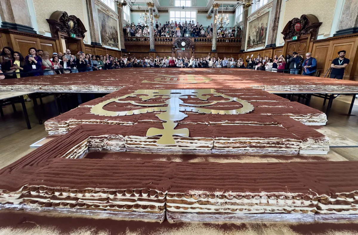 LONDON, UNITED KINGDOM - APRIL 26: A record-breaking tiramisu, measuring 440.58 meters, is displayed at Chelsea Old Town Hall in London, United Kingdom on April 26, 2026. Led by Italian entrepreneur Mirko Ricci and the London branch of the Federation of Italian Chefs, dozens of volunteers collaborated over two days to surpass the previous 273.5-meter record set in Milan in 2019. Guinness World Records official adjudicator Lorenzo Veltri verified the measurement on-site during the event, which was supported by the Italian Embassy and the Italian Cultural Institute. All proceeds from the organization were donated to the Esharelife Foundation to support efforts in combating poverty. Muhammed Yaylali / Anadolu (Photo by Muhammed Yaylali / Anadolu via AFP)