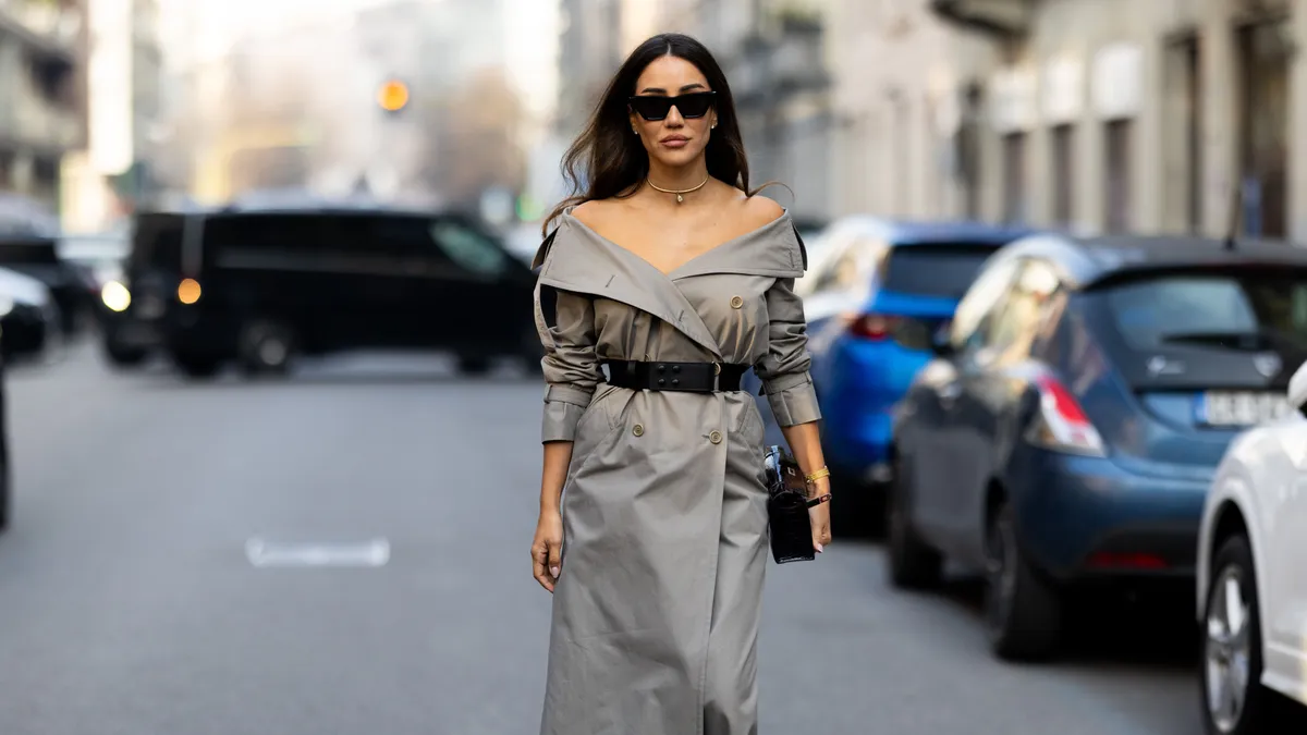 MILAN, ITALY - FEBRUARY 26: Tamara Kalinic wears diamond earrings, a gold watch, black sunglasses, a black leather Hermes Kelly bag, a gold chocker, a black leather belt and a beige trench midi dress outside Max Mara show during the Milan Fashion Week - Womenswear Fall/Winter 2026/2027 on February 26, 2026 in Milan, Italy. (Photo by Valentina Frugiuele/Getty Images)