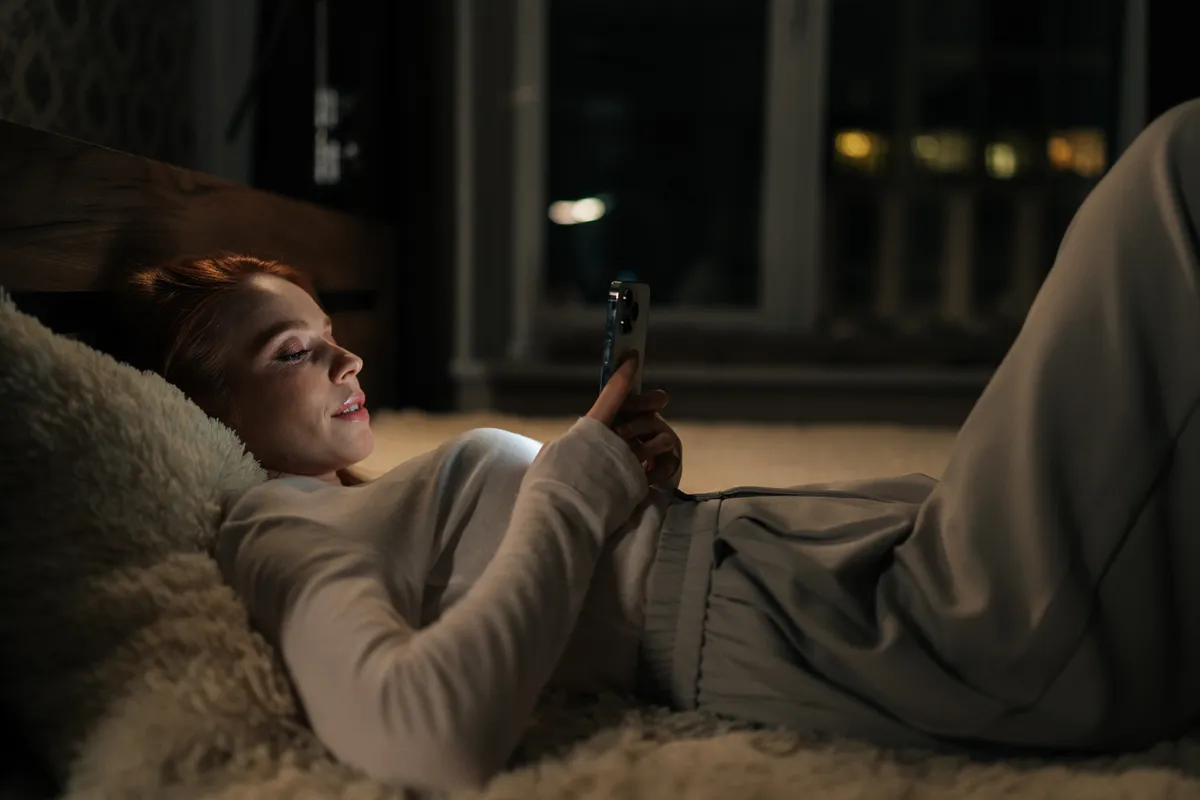 Ágyban fekvő nő a telefonját pörgeti. Vajon milyen személyiség lehet?